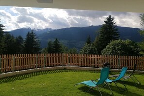 A patio with two chairs and a wooden fence overlooking a mountainous landscape. - Holiday apartment with 1 bedroom (Ramsau)