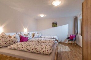 Une chambre avec deux lits, une chaise et un plancher en bois.