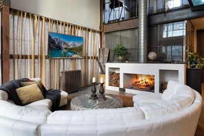 A modern living room with a fireplace, a round coffee table, and a sofa. - Melbourne City Apartments Luxury Loft House with rooftop (Southbank)