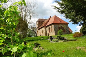 A stone church with a red roof, surrounded by greenery and a cemetery. - Holiday apartment with 1 bedroom (Vielist)