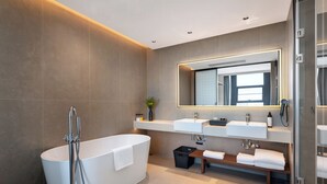 Une salle de bain moderne avec une baignoire sur pieds, deux vasques, un grand miroir et une douche à l’italienne.