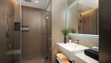 A modern bathroom with a glass-enclosed shower, a white sink, and a large mirror.