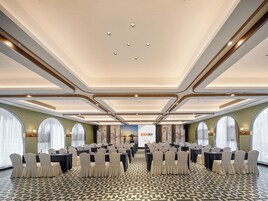 Un salón de conferencias con mesas y sillas dispuestas para una reunión.