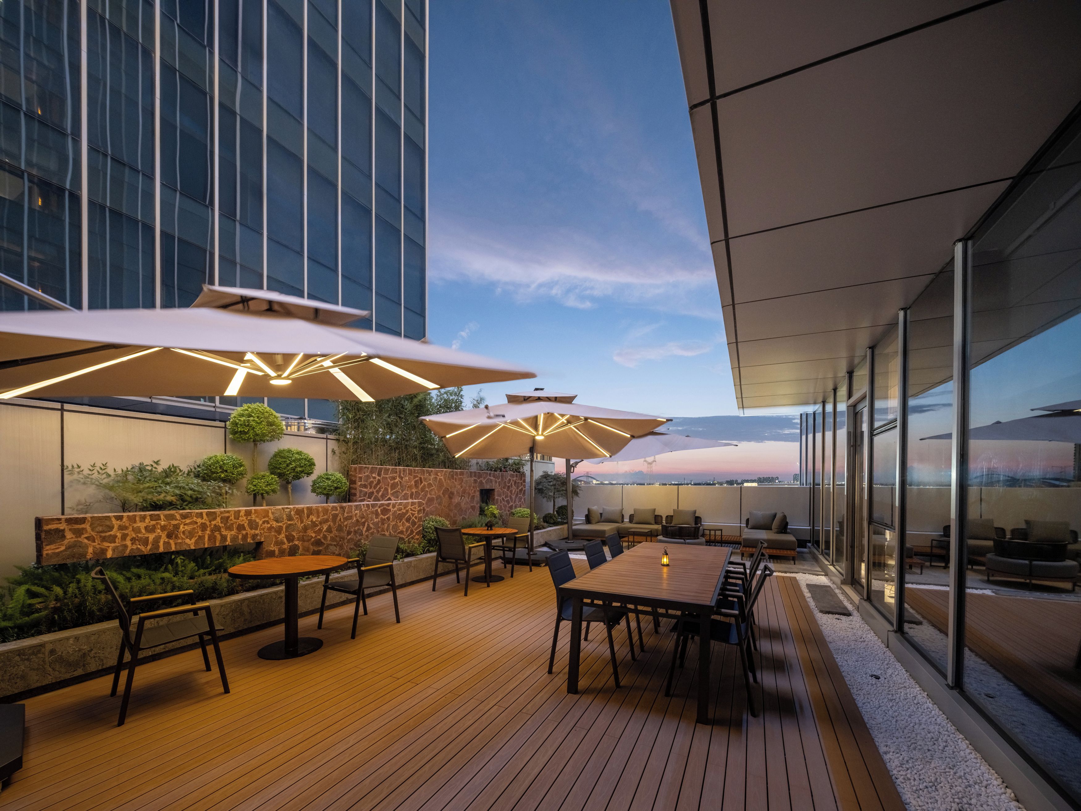 An outdoor patio area with tables and chairs, umbrellas, and a view of the city skyline.