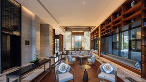 Un intérieur moderne avec un coin salon, des étagères en bois et de grandes fenêtres.