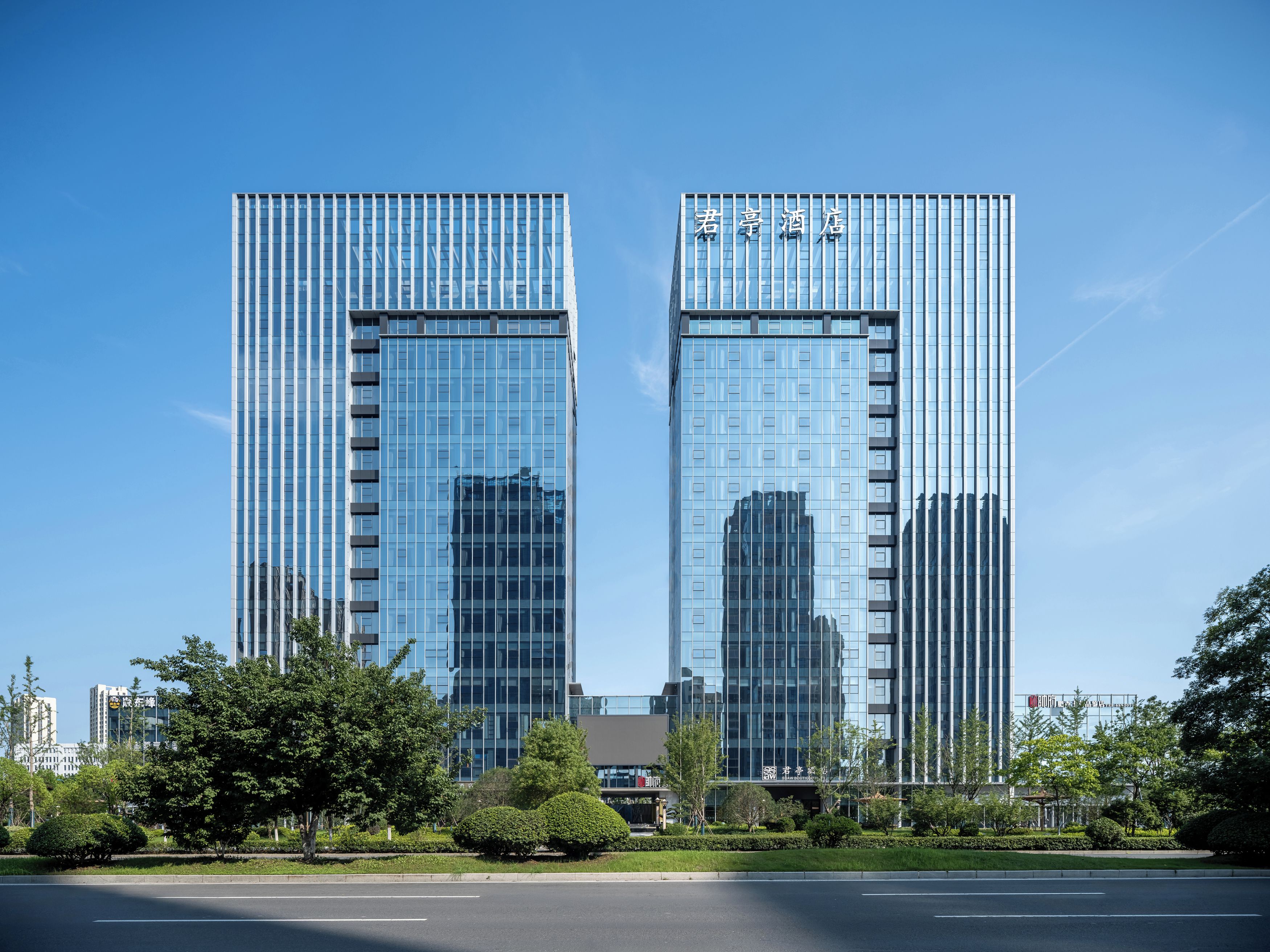 A modern hotel with a glass facade, two-story structure, and a clear sky.