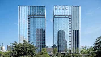 A modern hotel with a glass facade, two-story structure, and a clear sky.