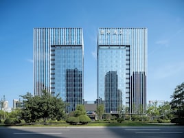 Un hotel moderno con fachada de vidrio, estructura de dos pisos y cielo despejado.