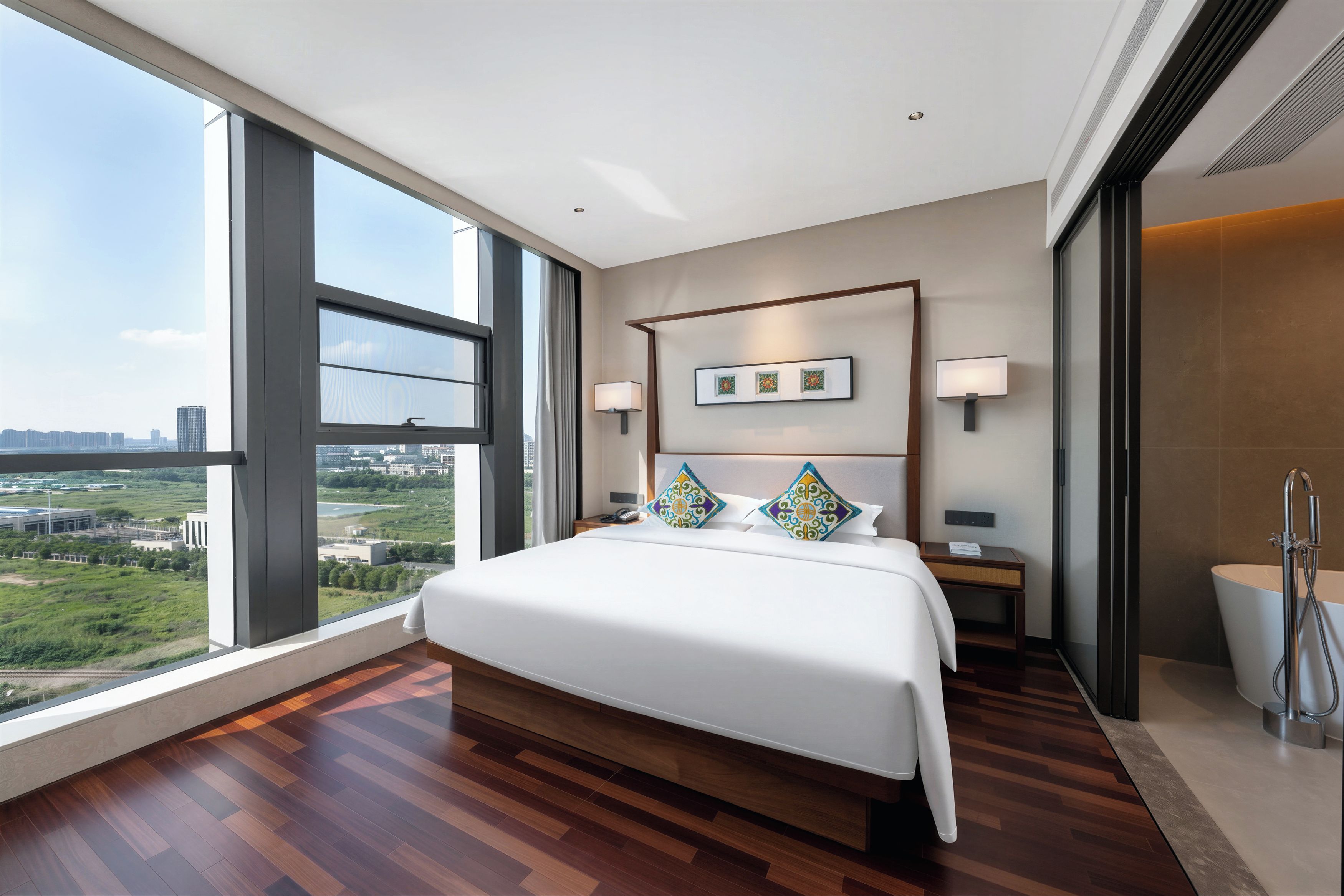 Habitación de hotel moderna con una cama grande, vistas a la ciudad y un baño independiente.