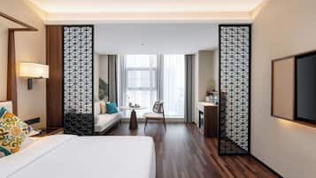 A hotel room with a bed, a desk, a chair, a TV, and a large window with curtains.