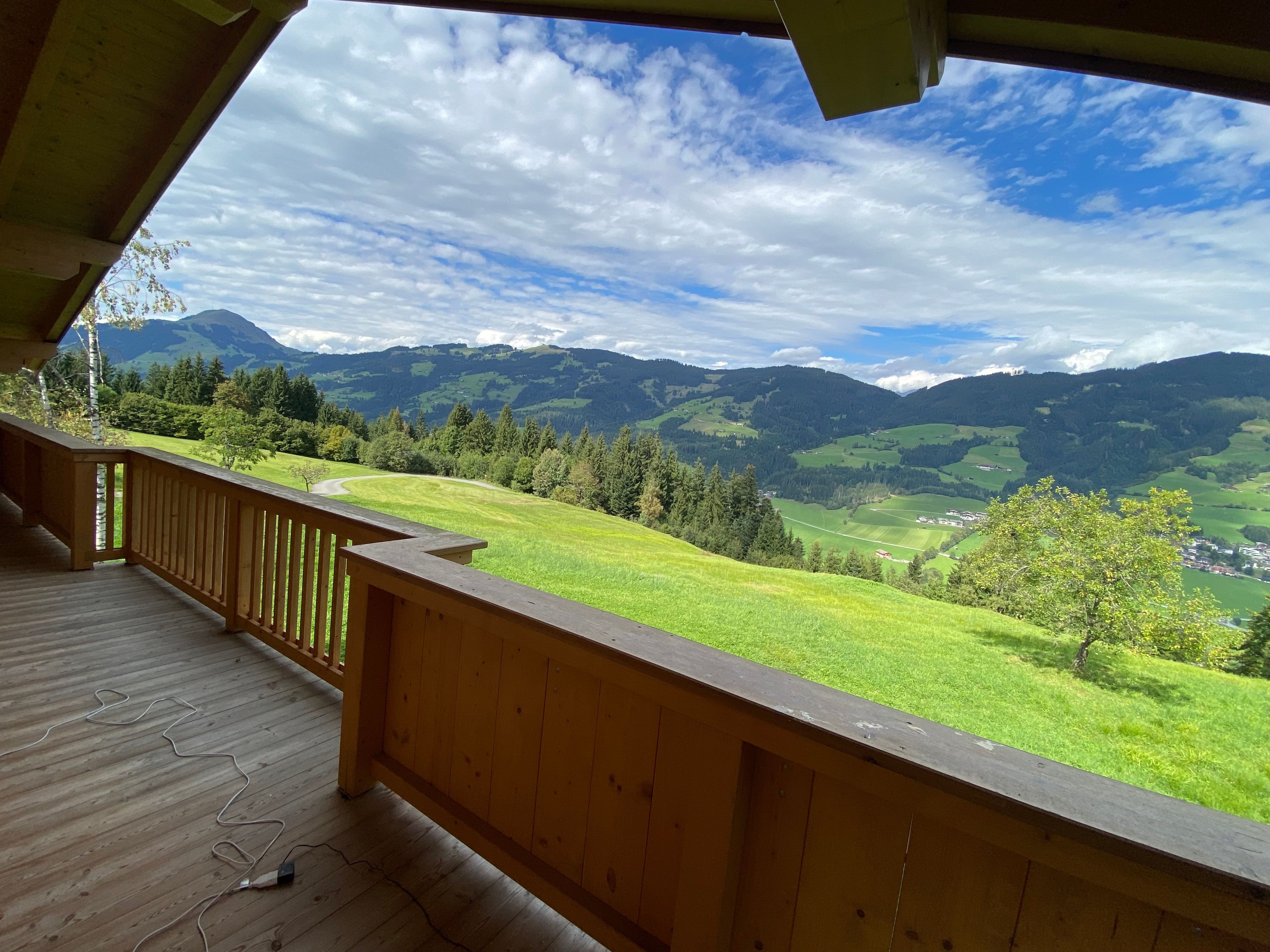 A wooden deck with a view of green hills and mountains.