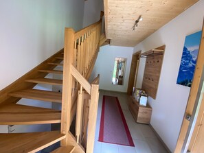 A wooden staircase leading to an upper floor, a hallway with a red rug, and a wooden cabinet with boxes. - Holiday Home 'Landhaus Kreidl' with Mountain View, Shared Terrace and Wi-Fi (Kirchberg in Tirol)