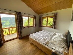 A bedroom with a wooden ceiling, a large bed, and two windows with curtains. - Holiday Home 'Landhaus Kreidl' with Mountain View, Shared Terrace and Wi-Fi (Kirchberg in Tirol)