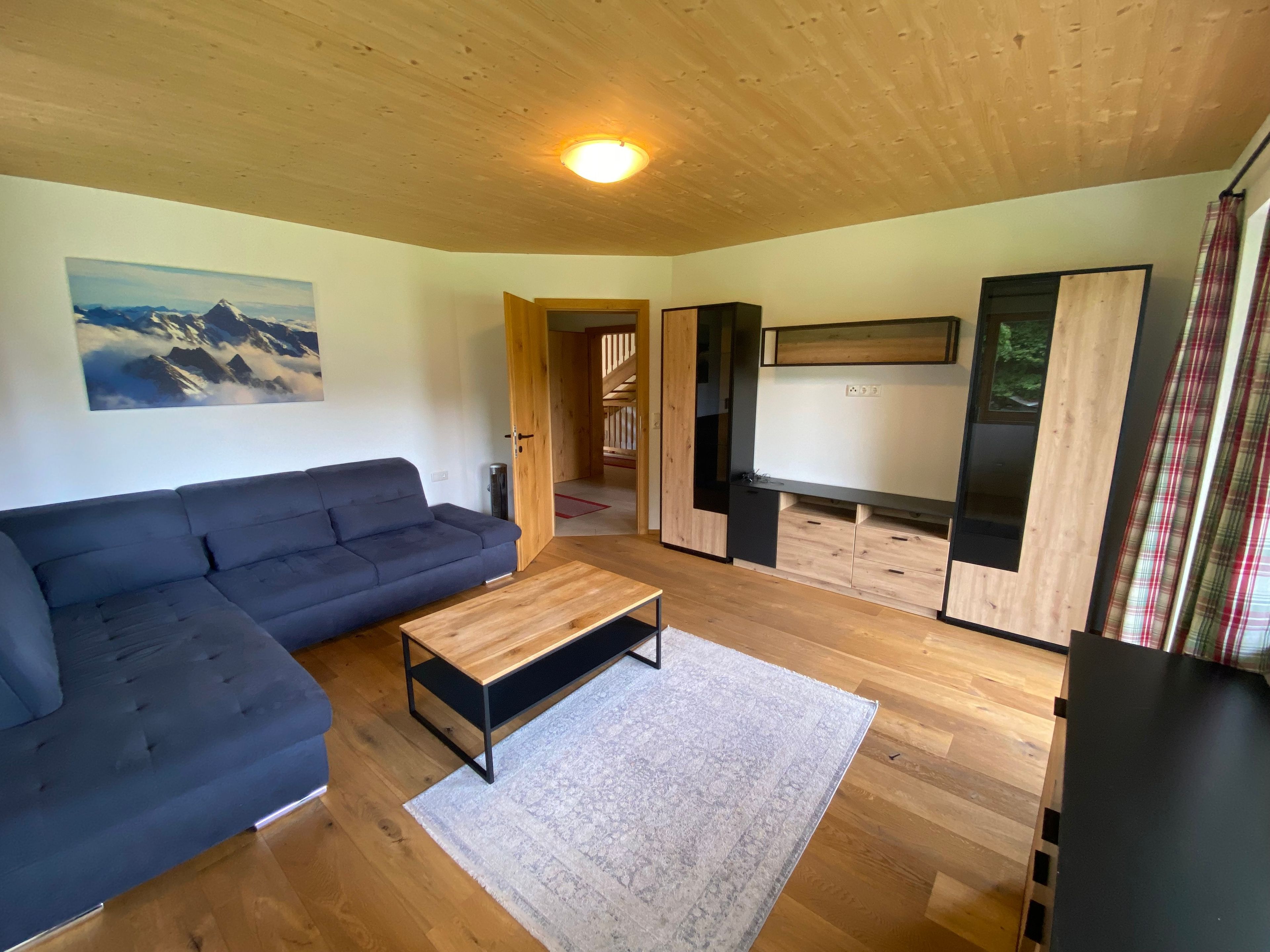 A modern living room with a dark sofa, a wooden coffee table, and a flat-screen TV.