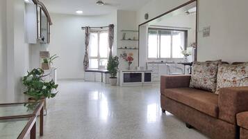 Amplia sala de estar con sofá, mesa de comedor y cocina al fondo.