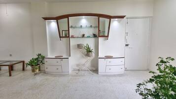 Una habitación con un armario blanco, una cómoda con espejo y una planta en una repisa.