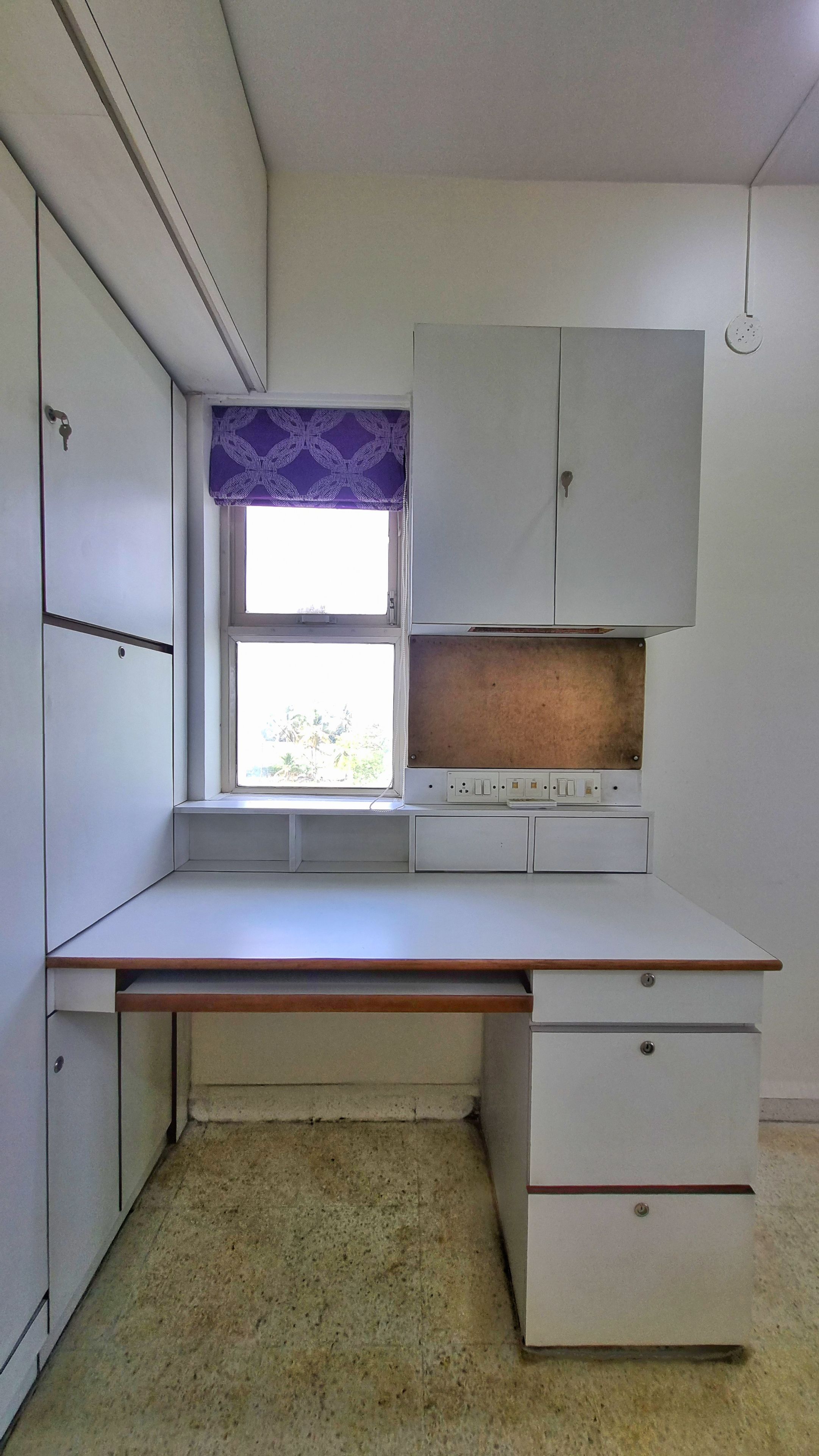 A small, compact kitchen with a window, built-in cabinets, and a countertop.