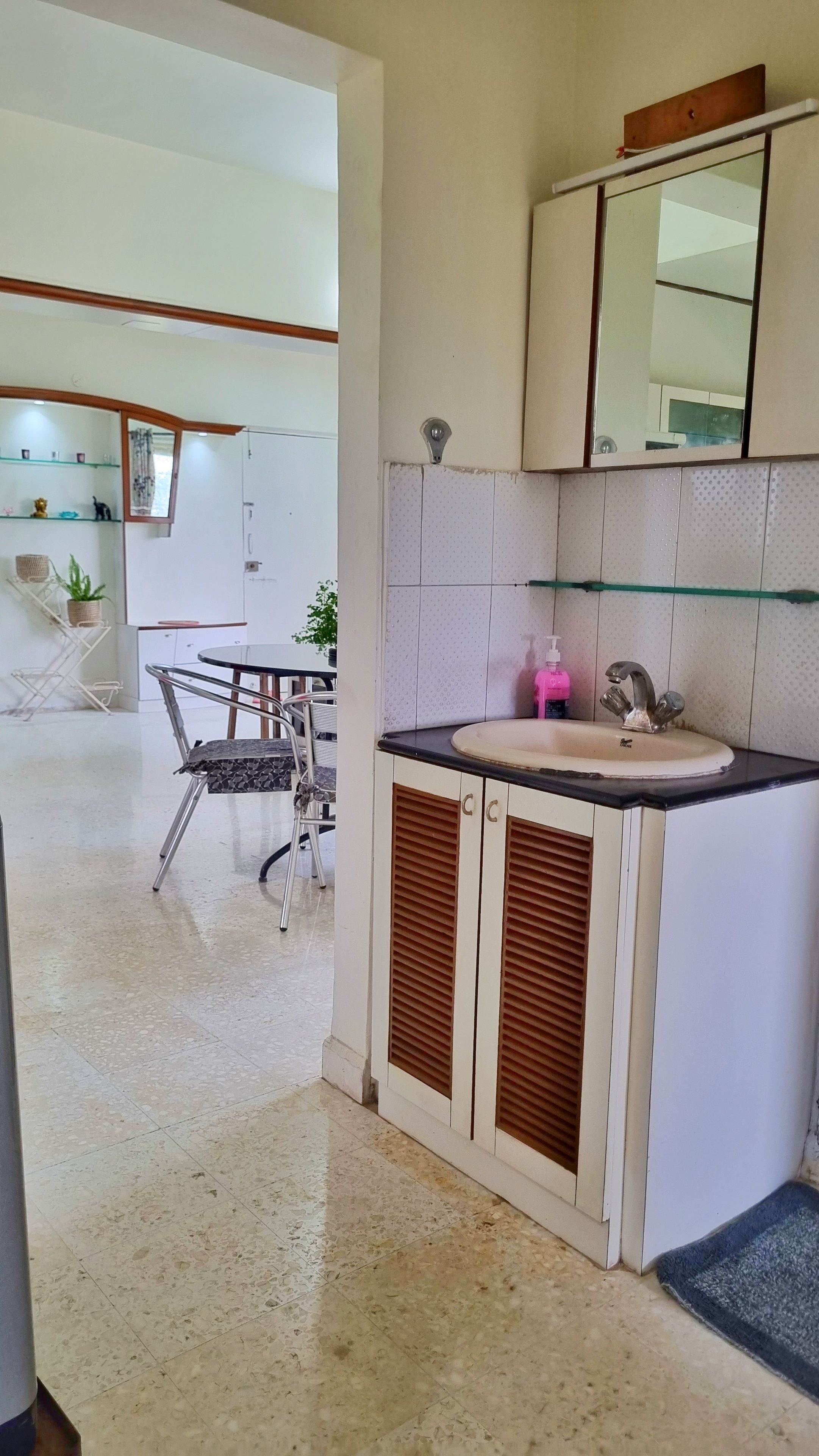 A modern kitchen with a sink, mirror, and a dining area with chairs and a table.