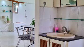 A modern kitchen with a sink, mirror, and a dining area with chairs and a table.