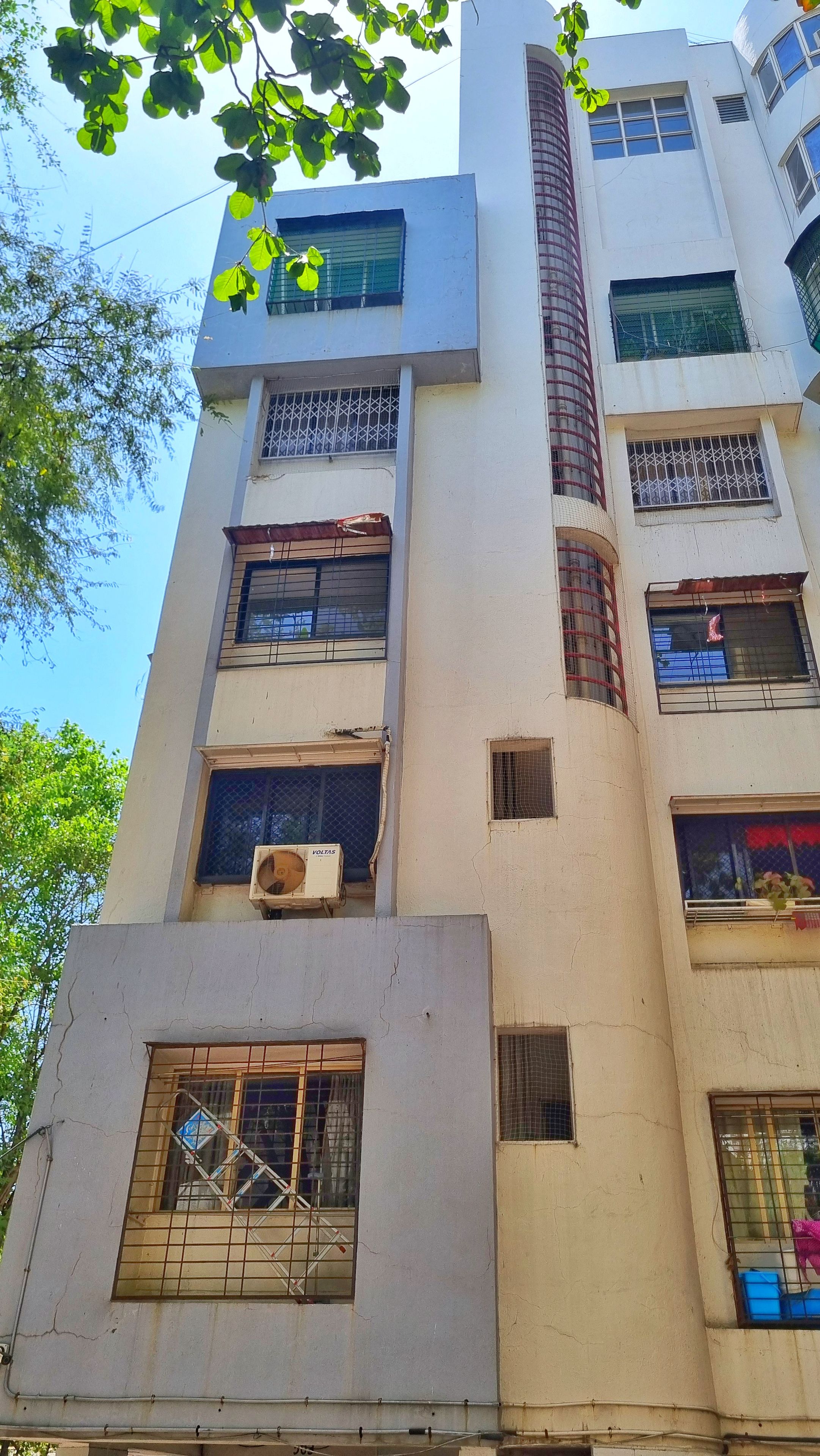 A multi-story building with multiple windows, some with metal grilles, and a visible air conditioning unit on one of the lower floors.