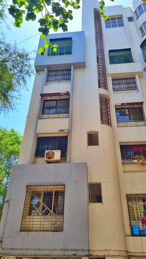A multi-story building with multiple windows, some with metal grilles, and a visible air conditioning unit on one of the lower floors.