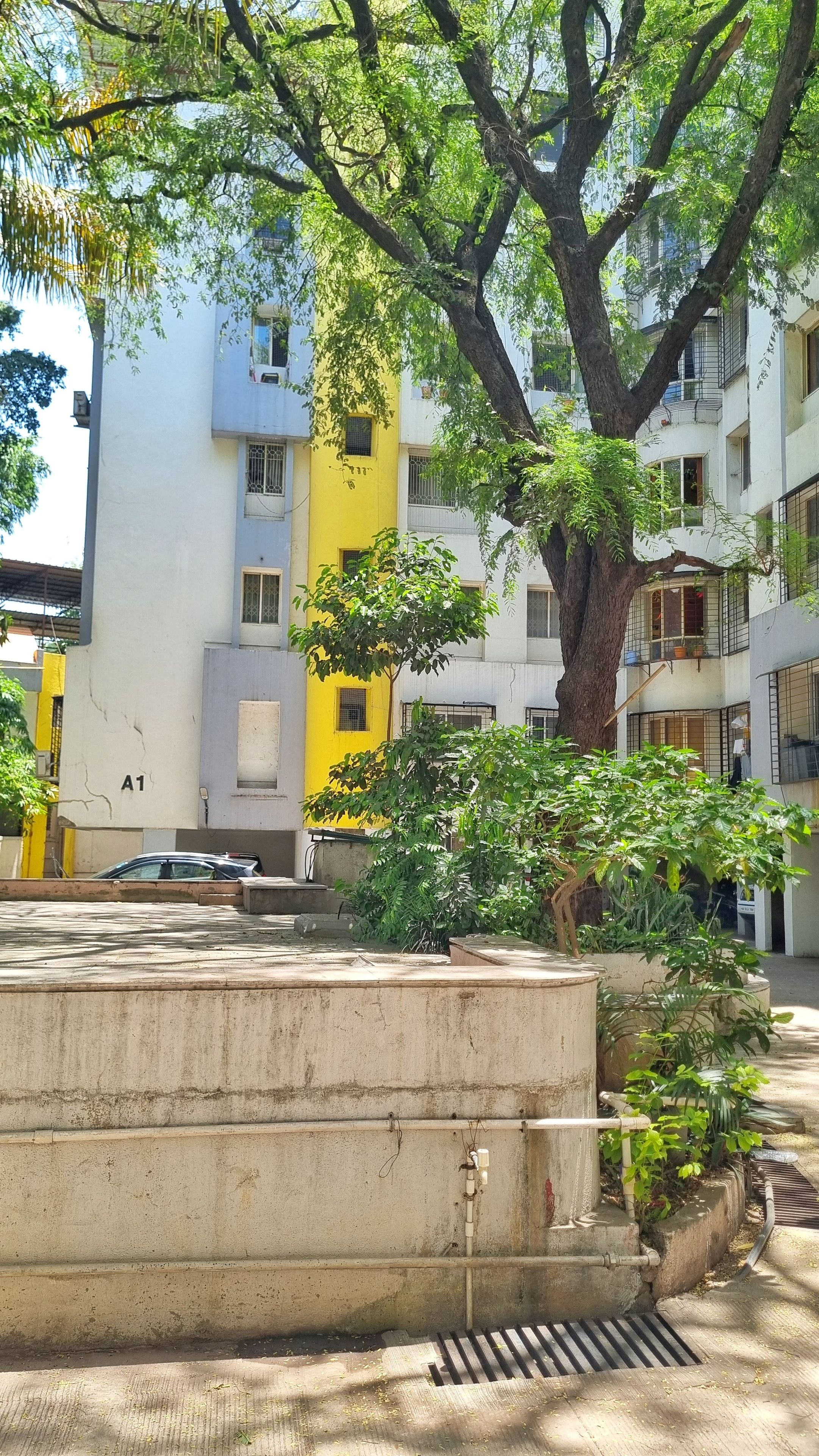 Zona residencial con edificios de varios pisos, un árbol y una estructura de concreto.