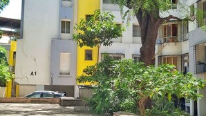 Zona residencial con edificios de varios pisos, un árbol y una estructura de concreto.