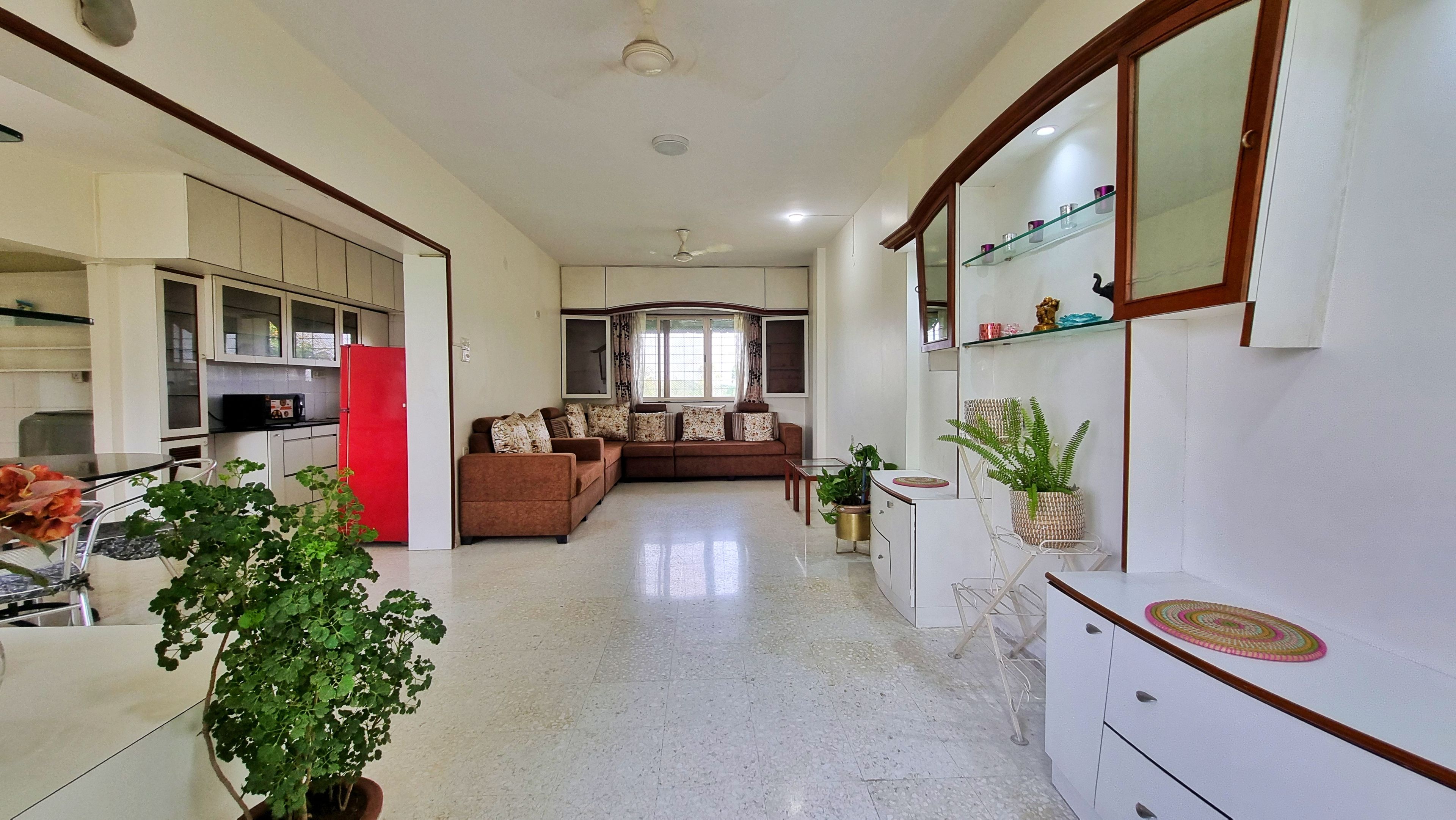 Amplia sala de estar con un juego de sofás, una mesa de comedor y una cocina con un refrigerador rojo.