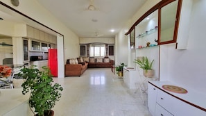 Amplia sala de estar con un juego de sofás, una mesa de comedor y una cocina con un refrigerador rojo.