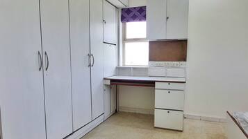 Et værelse med et tekøkken, en stor garderobe og et vindue med gardin med et mønster.