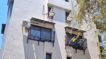 Ein mehrstöckiges Gebäude mit Balkonen, Klimaanlagen und einem Parkplatz mit Autos.