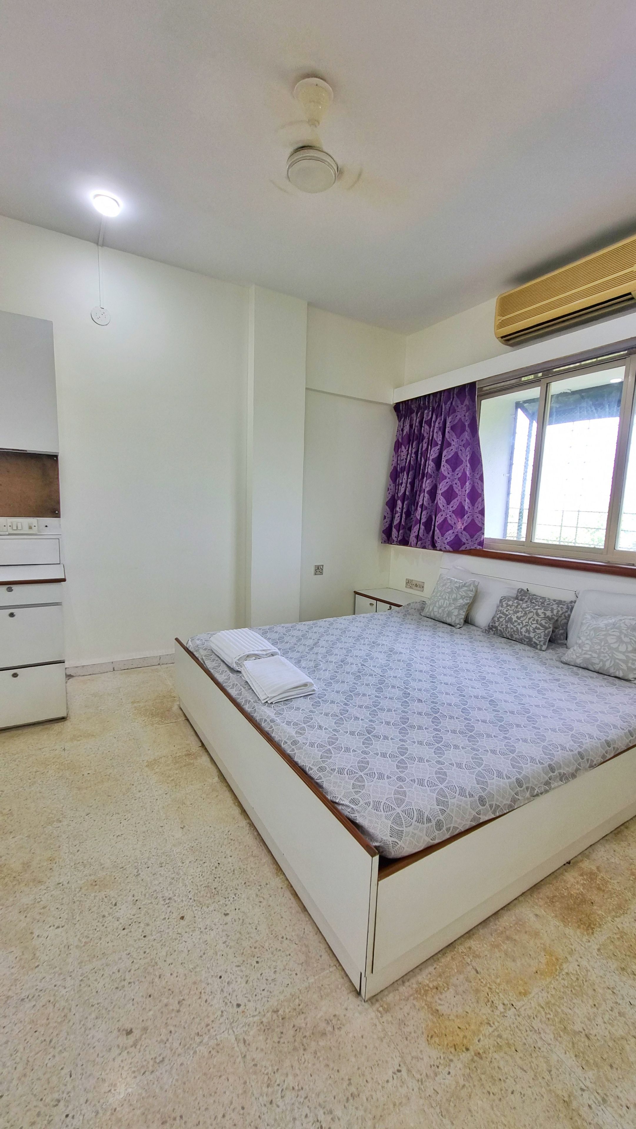 A bedroom with a bed, a dresser, a window with curtains, and a ceiling fan.