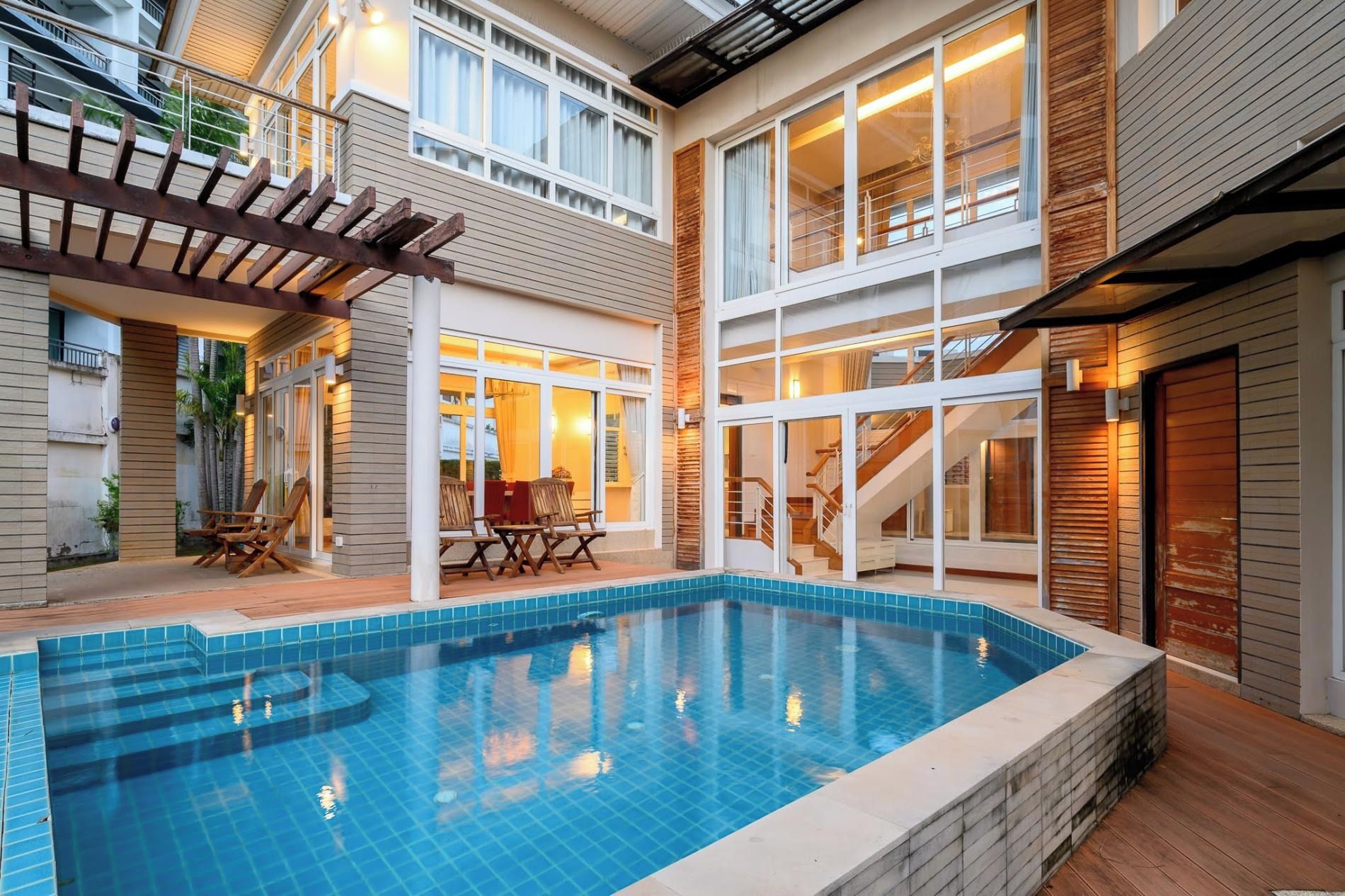 Un immeuble résidentiel doté d’une piscine, d’une terrasse en bois et d’un patio couvert.