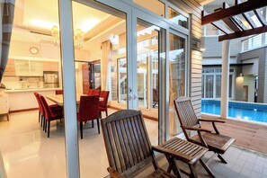 Ein modernes Interieur mit Essbereich, Küche und Blick auf einen Swimmingpool.