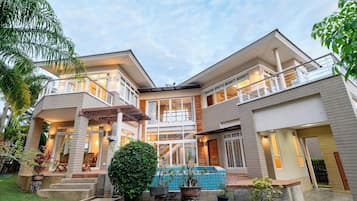 Une maison à deux étages dotée d’un patio couvert, d’une piscine et d’un jardin bien entretenu.