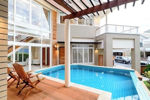 A modern residential building with a swimming pool, wooden deck, and a car parked outside. - Modern 2BR Beachside Pool Villa (BA2) (Sattahip)