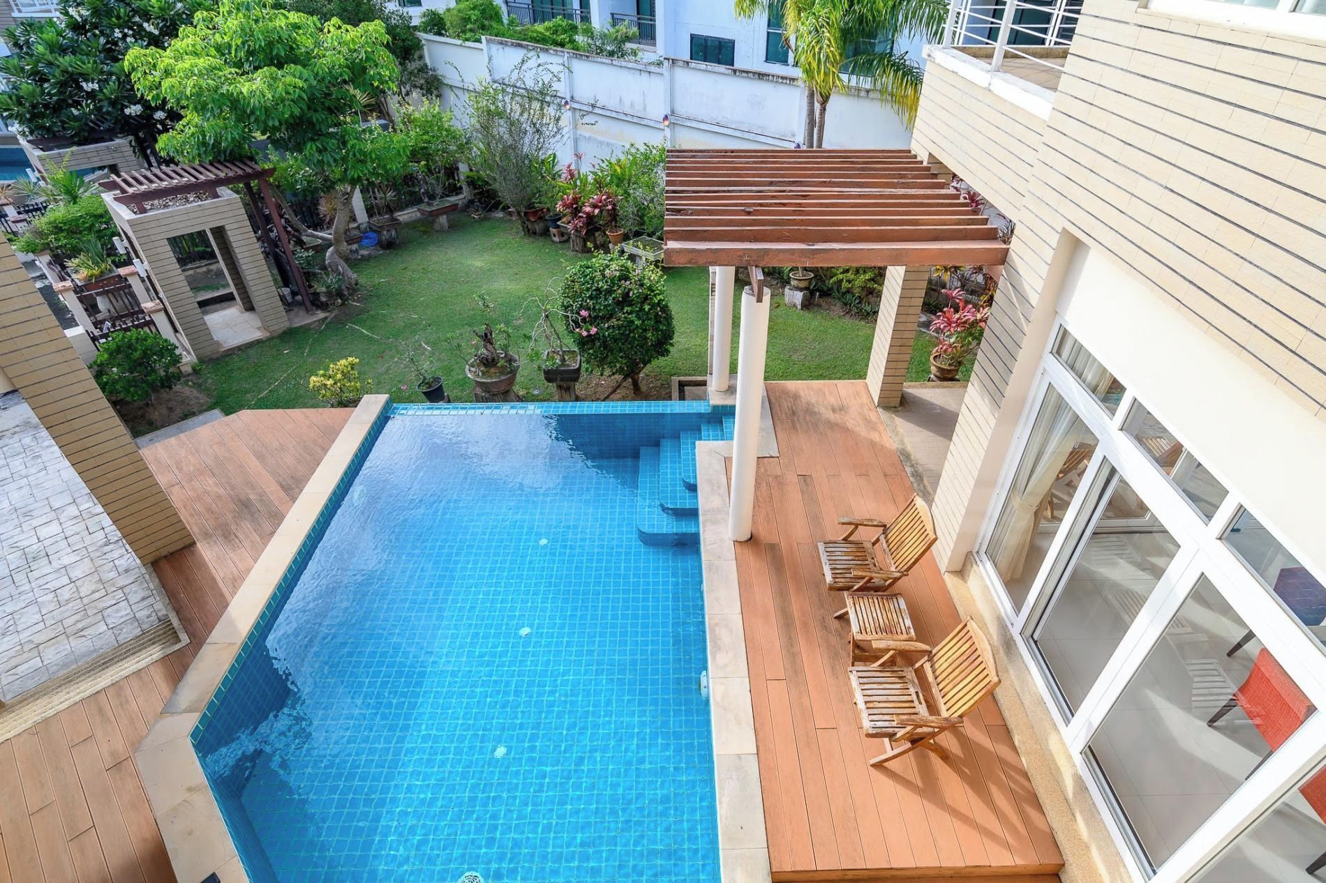 A rectangular swimming pool with a wooden deck and outdoor furniture.