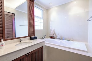 Ein Badezimmer mit einer großen Badewanne, einem Waschbecken, einem Spiegel und einem Fenster.
