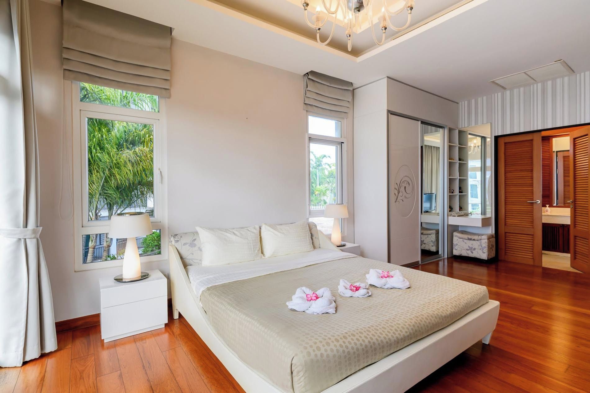 Une chambre d’hôtel comprenant un lit, des tables de chevet, une armoire et une salle de bain avec un miroir.