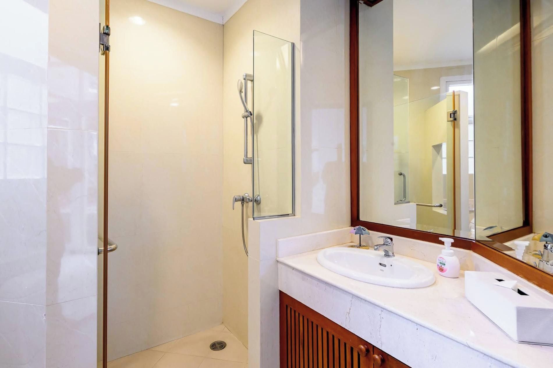 A modern bathroom with a glass-enclosed shower, a white sink, and a large mirror.