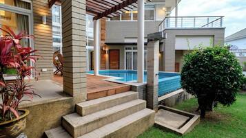 Uma casa moderna com piscina, varanda coberta e jardim bem cuidado.