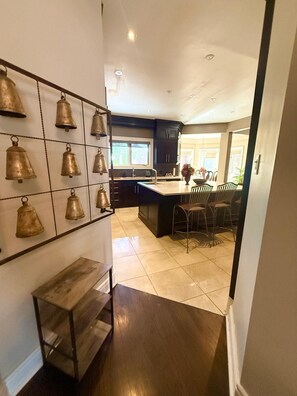 A modern kitchen with a central island, dark cabinetry, and a wall-mounted bell collection. - Erin Mills Mall • Self Check-in • 2 min to Transit (Mississauga)