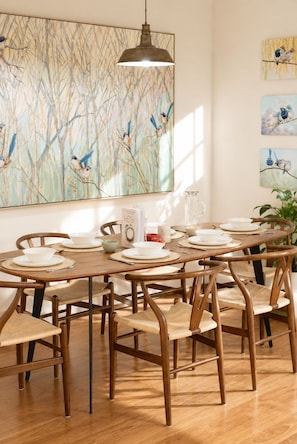 A dining area with a wooden table set for six, surrounded by wooden chairs with woven seats. - The Sunlit Verandah | Charming Timber Retreat (Annerley)