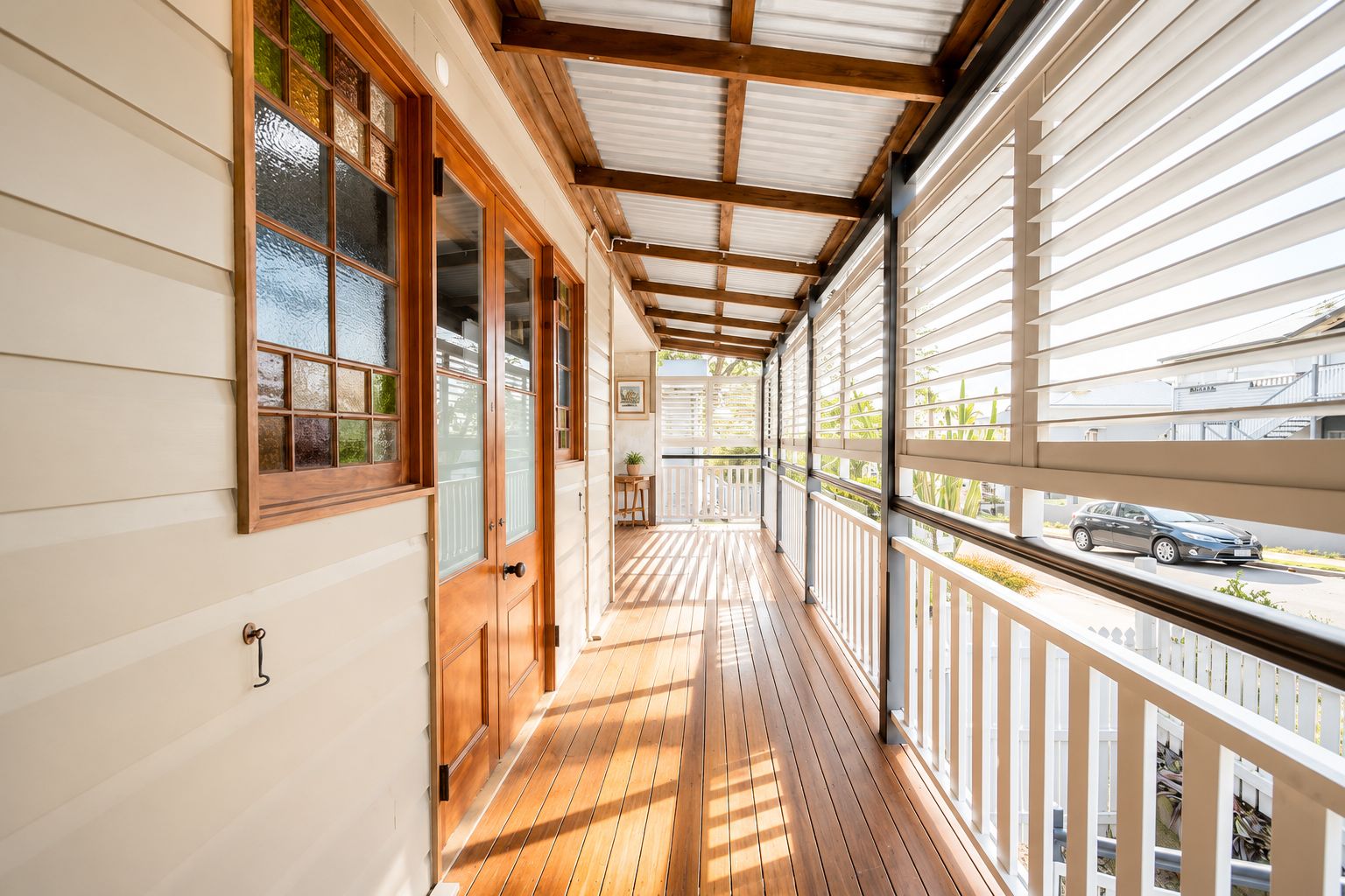A covered wooden deck with a view of the street.