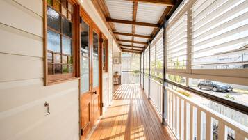 A covered wooden deck with a view of the street.