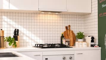 A modern kitchen with white cabinetry, a gas stove, and a tiled backsplash.