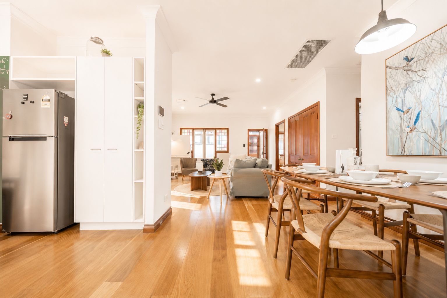 Una cocina moderna con refrigerador empotrado, mesa de comedor de madera y sillas.