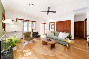 A spacious living room with a sofa, armchairs, a coffee table, and a TV.