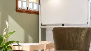 A room with a whiteboard, a wooden desk, a green chair, and a window with stained glass.