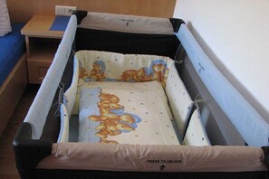 A crib with a bear-themed mattress and a 'Press to Unlock' label. - Holiday apartment with 2 bedrooms (Sölden)